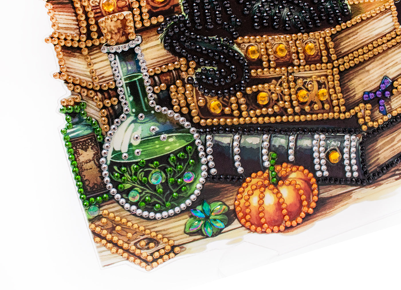 Decorative item with beaded design featuring a potion bottle, pumpkin, and books on a white background