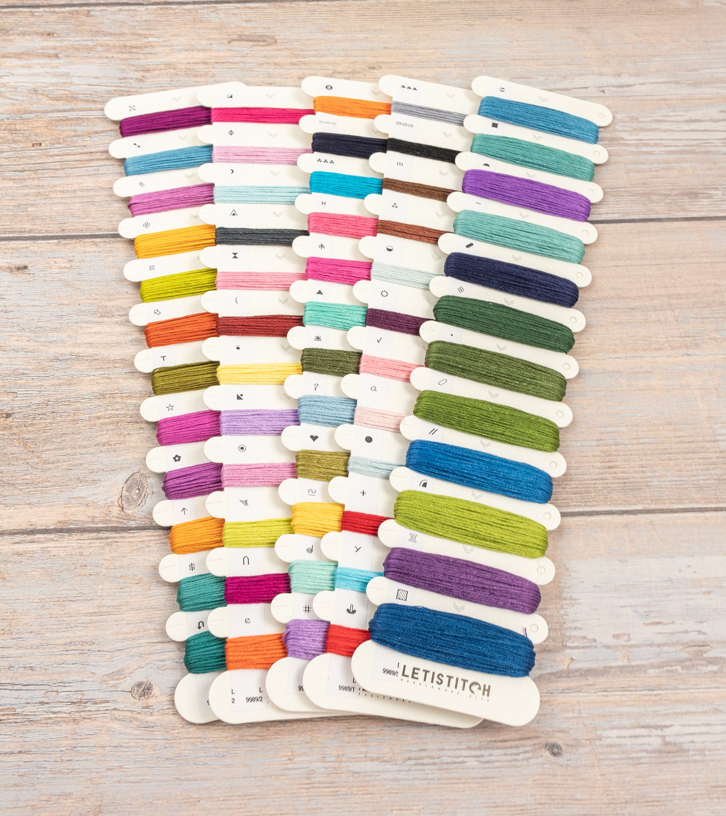 Set of colorful embroidery threads on a wooden surface with 'LetiStitch' branding.