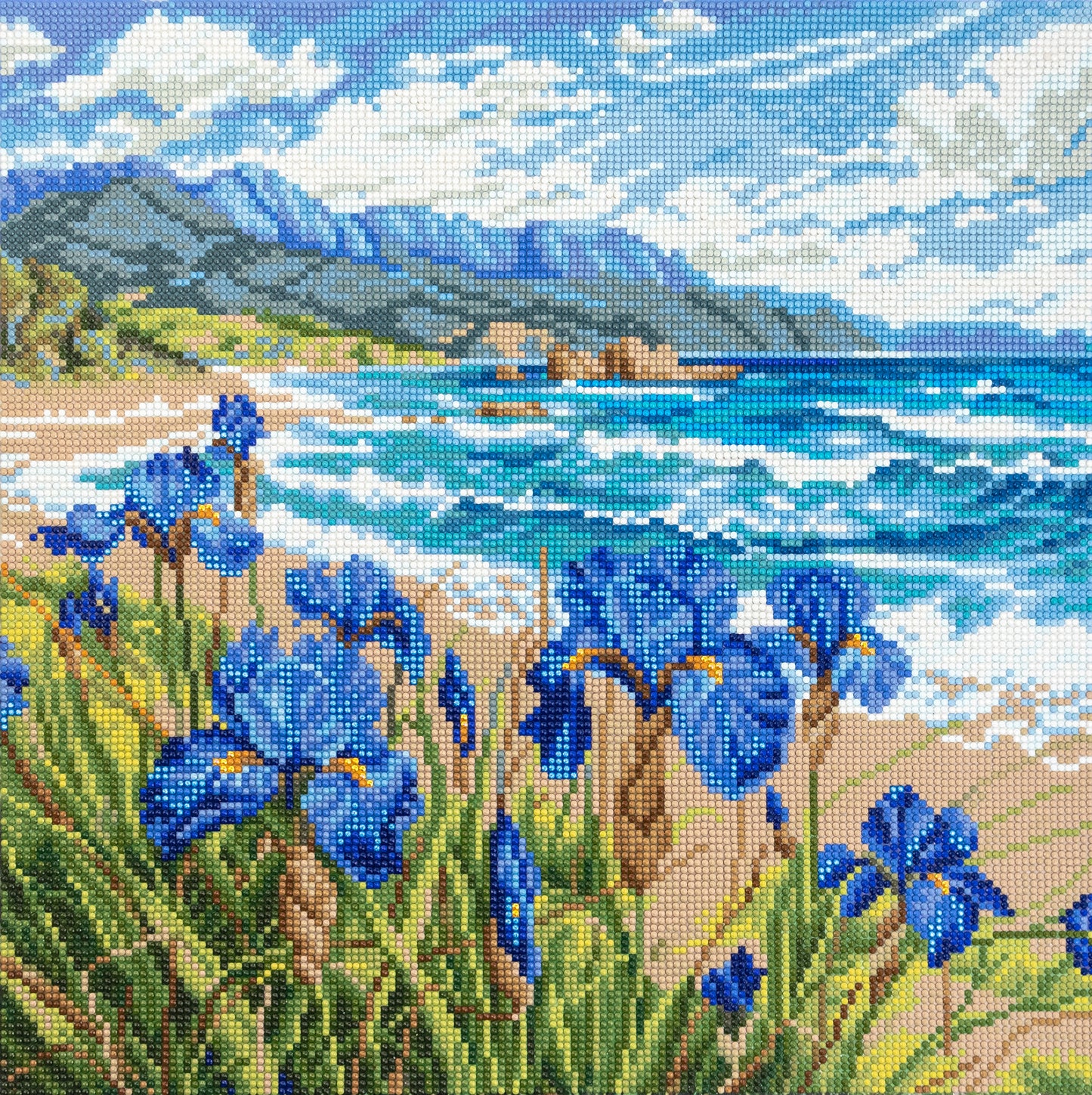 Diamond painting of blue flowers by a lake with mountains in the background