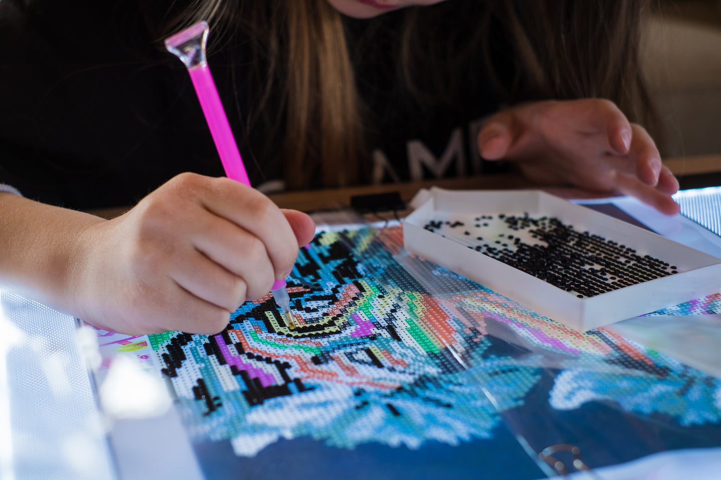 Person working on a Diamond Art kit project with colorful patterns