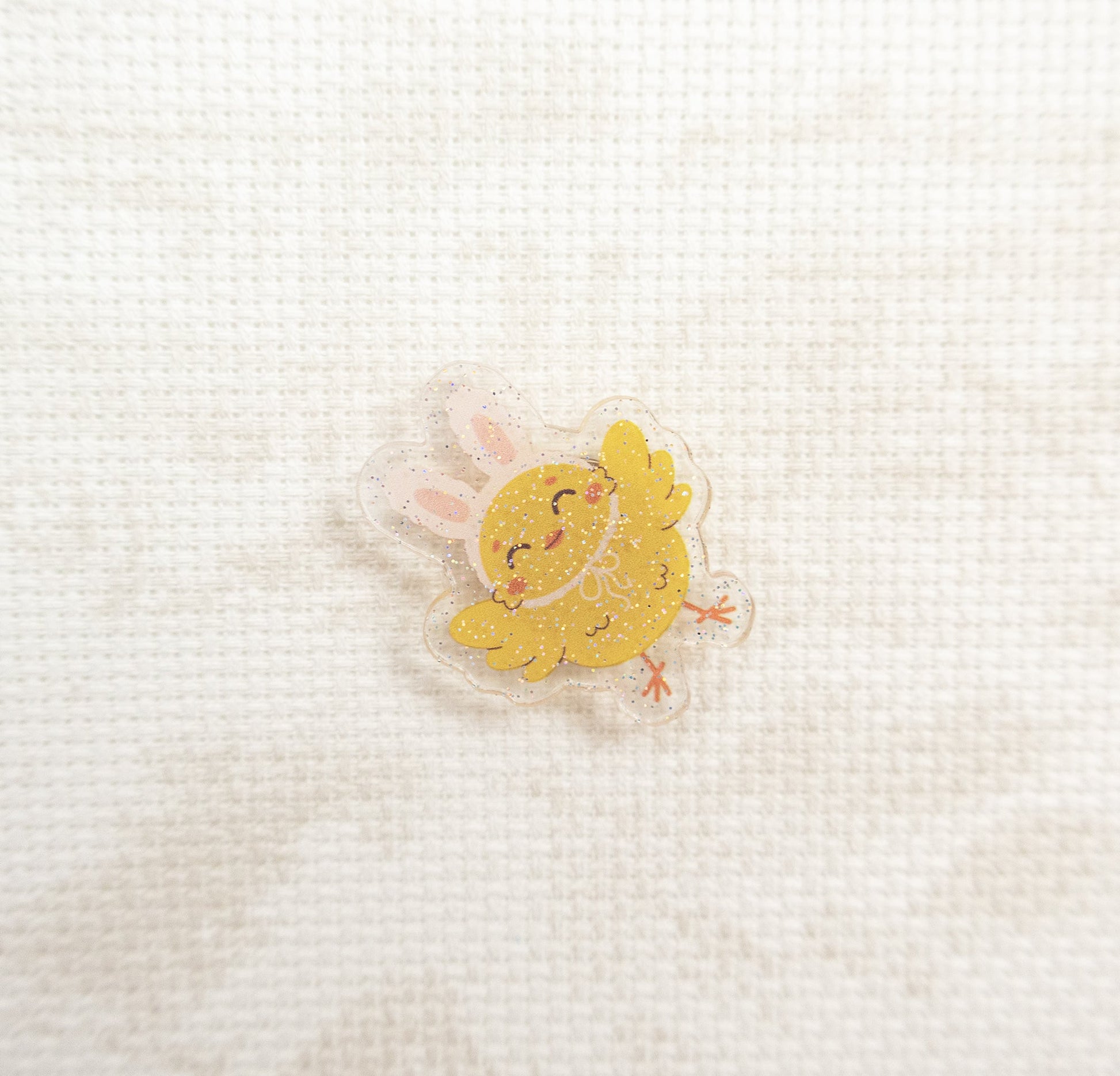Yellow chick charm on a textured white background