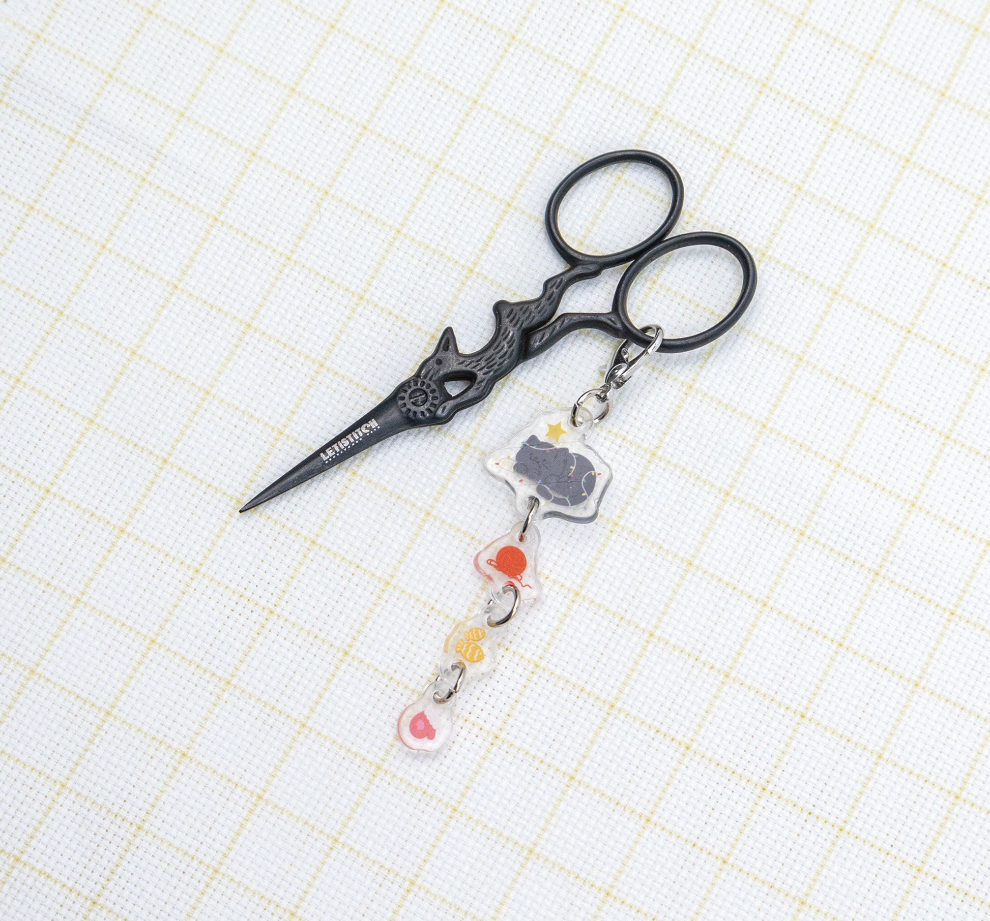 Decorative scissors with a keychain on a grid background
