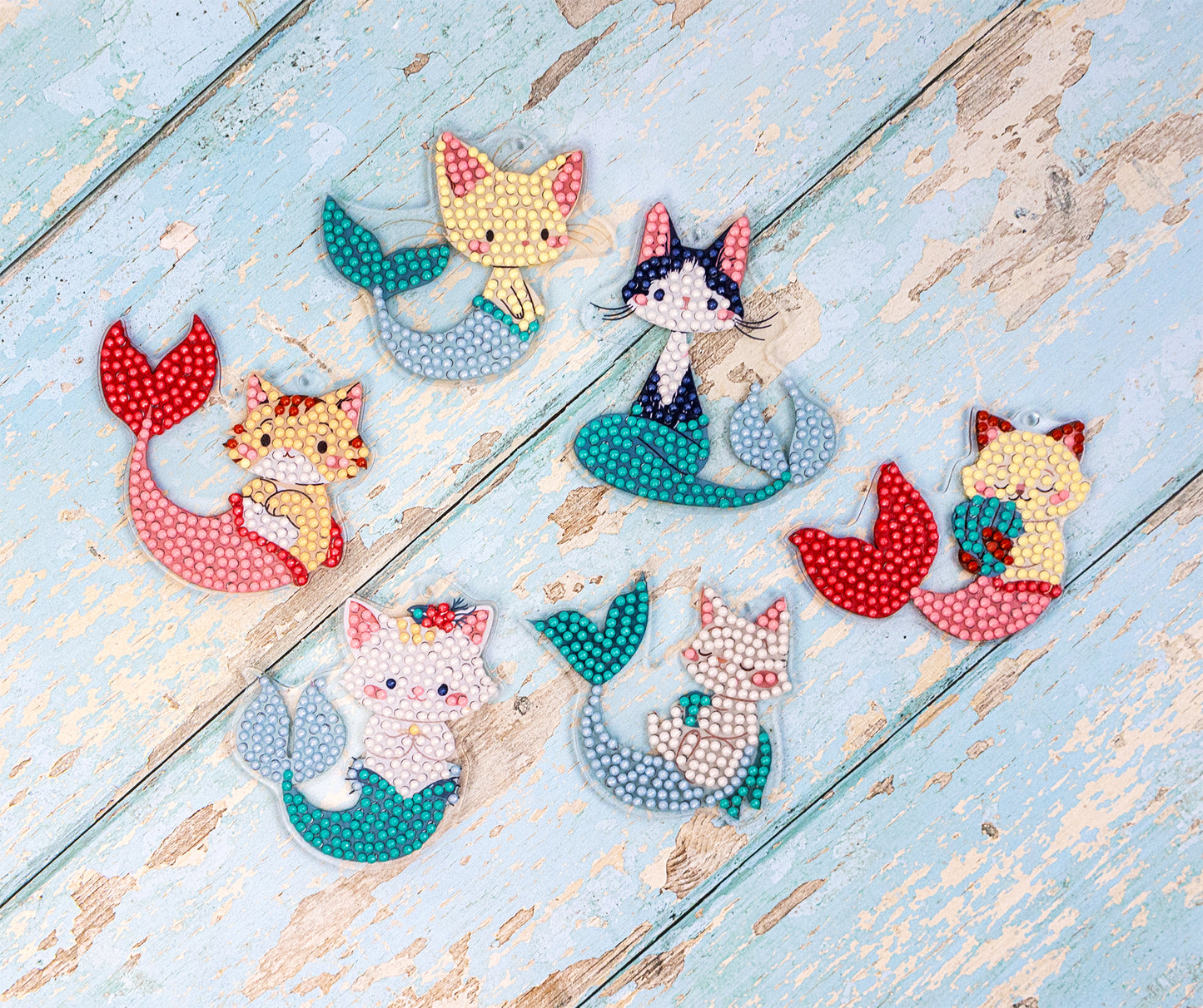 Set of cat-themed mermaid figurines on a wooden surface