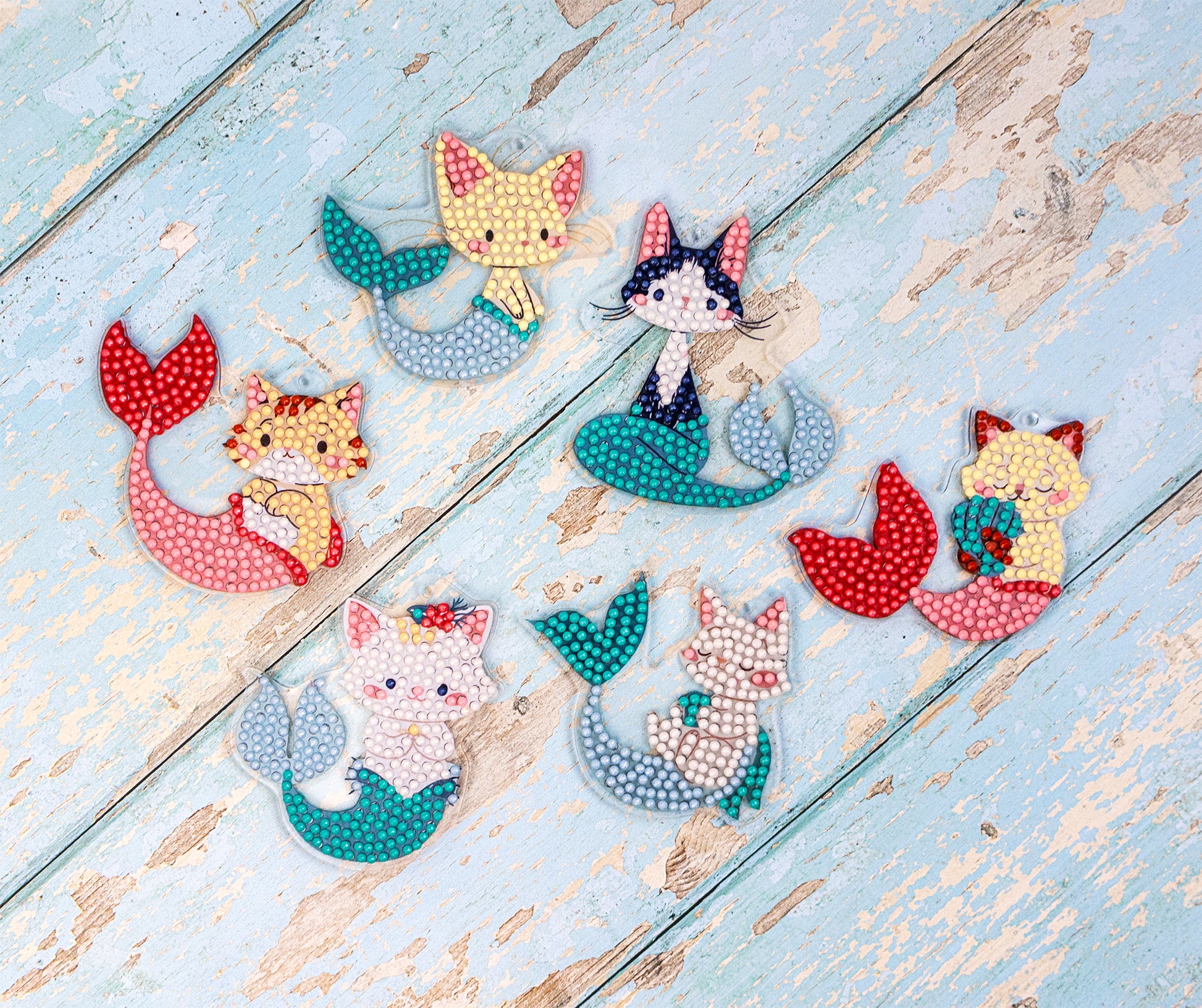 Set of cat-themed mermaid figurines on a wooden surface