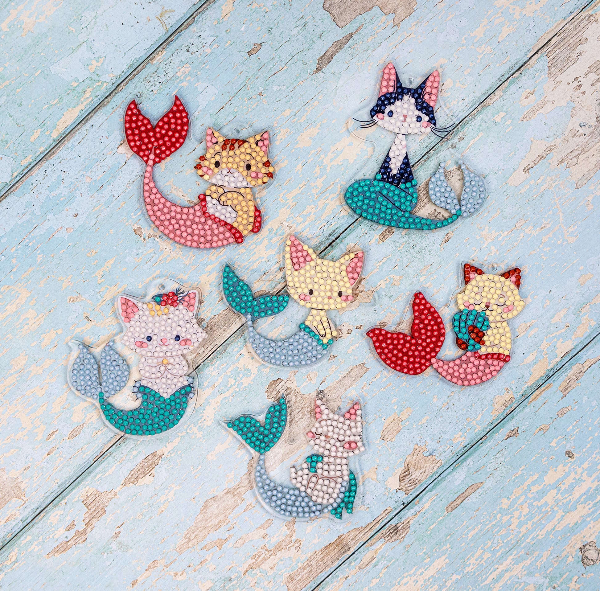 Set of cat-themed mermaid brooches on a wooden surface