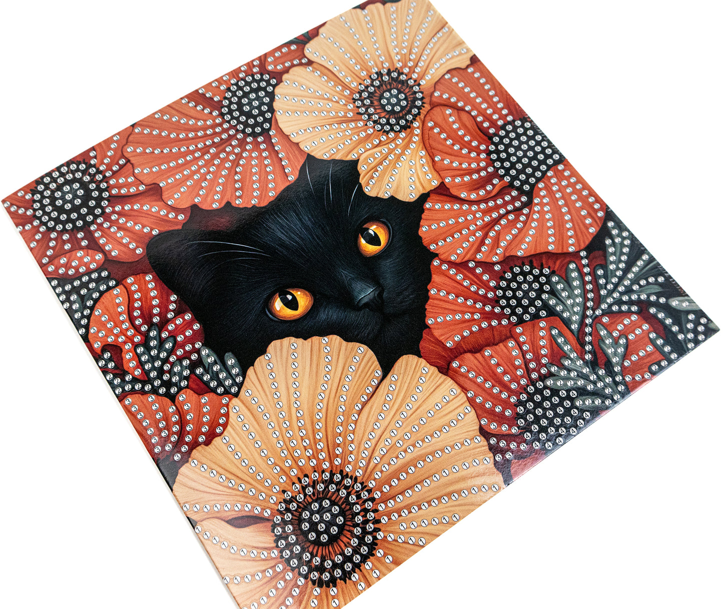 Black cat with orange eyes peeking out from a decorative surface with floral patterns