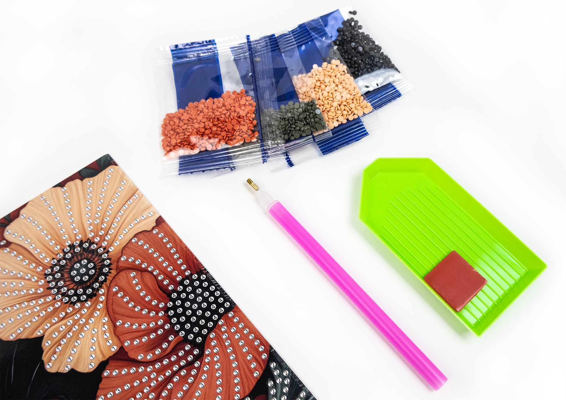 crystal art card with embellishments, pink pencil, and small containers of beads on a white background