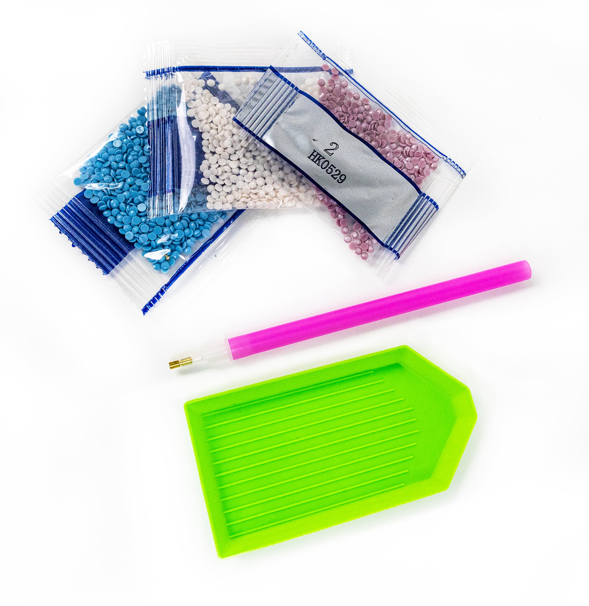 Assorted craft supplies including crystals, a pen, and a green tray on a white background