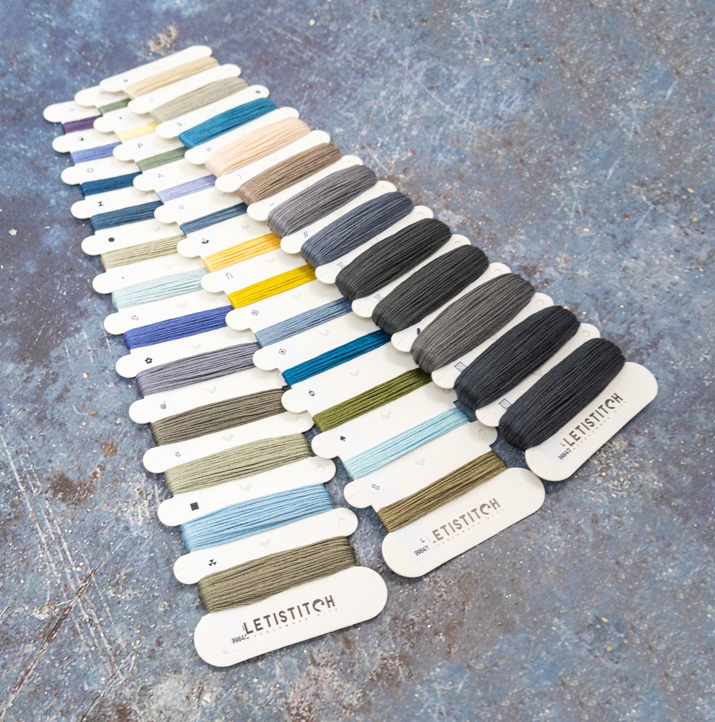Set of embroidery threads in various colors on a textured surface