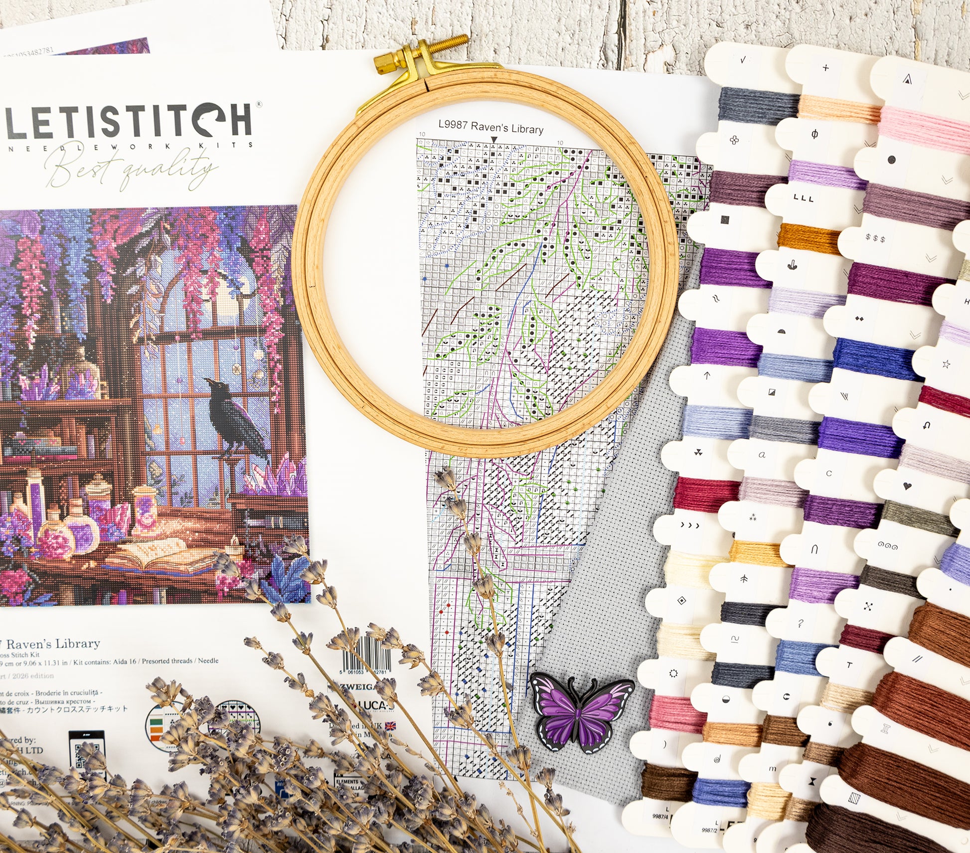 Embroidery hoop with pattern, threads, and decorative elements on a wooden surface.