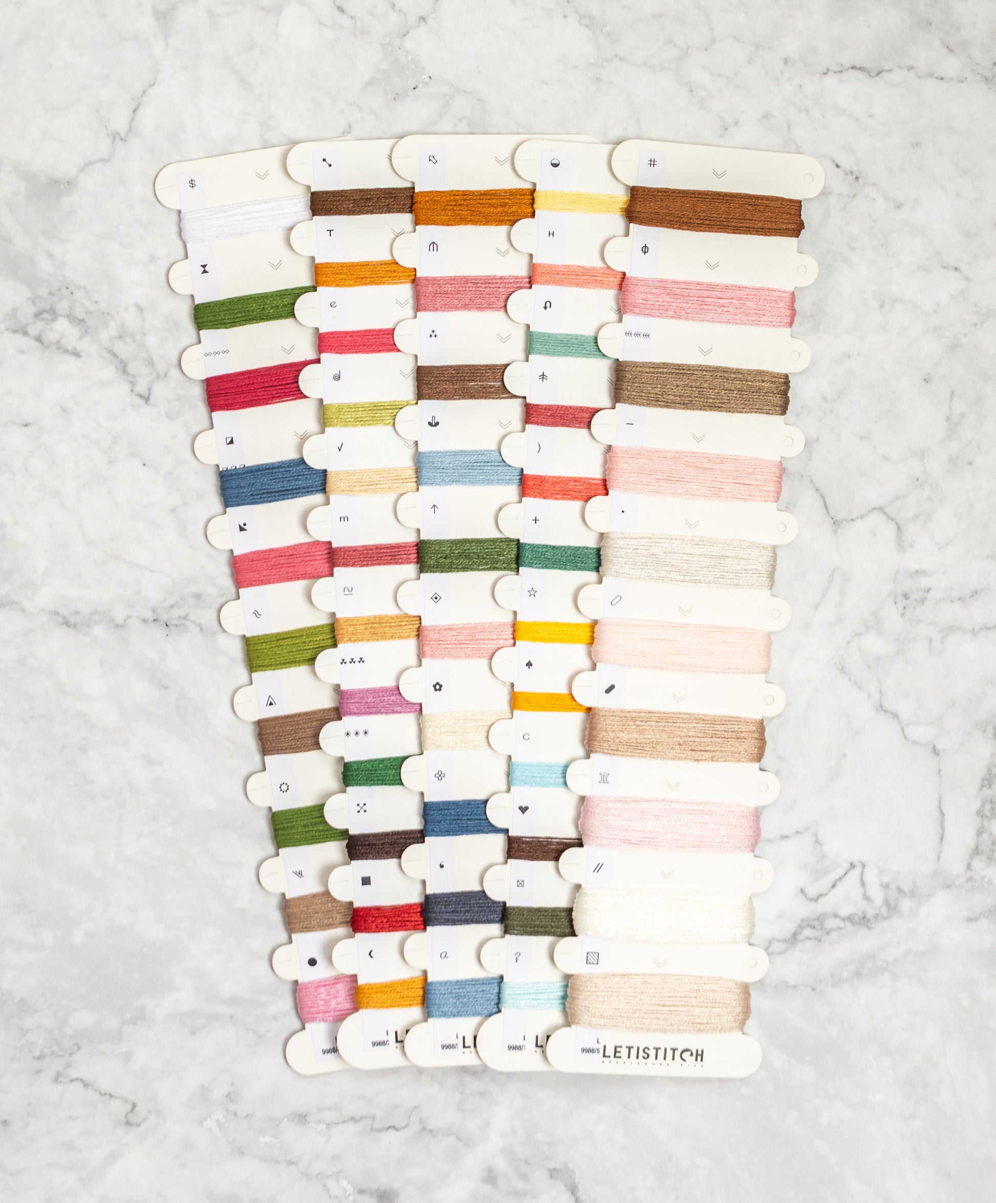 Collection of colorful thread spools on a marble surface