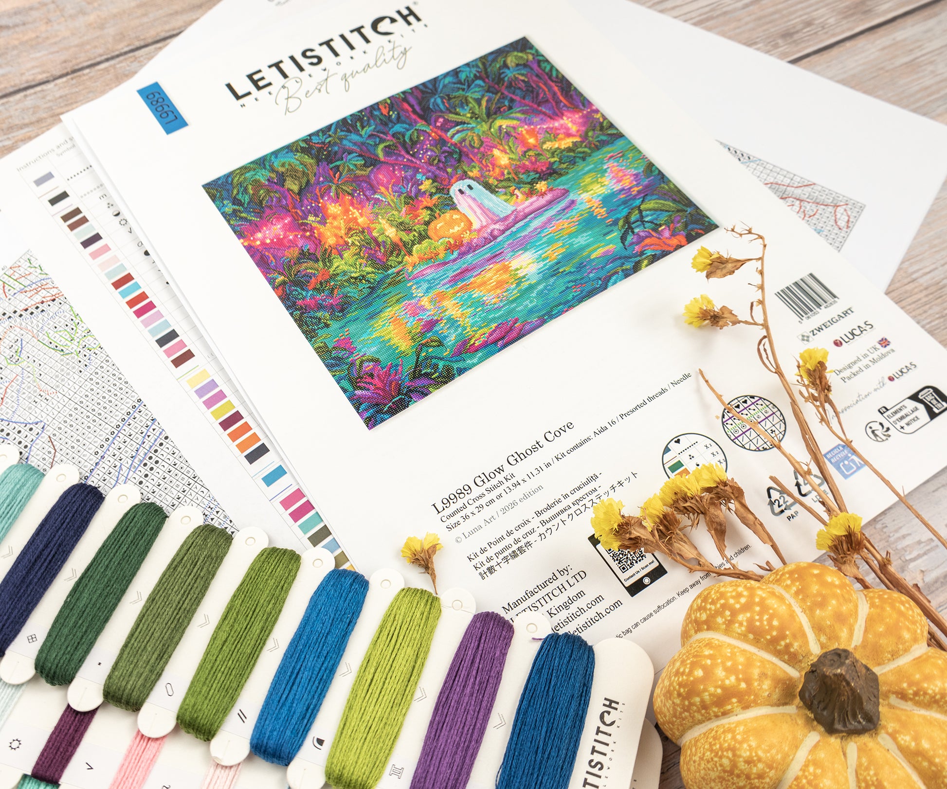 Embroidery kit with colorful fabric design, threads, and a pumpkin on a wooden surface.