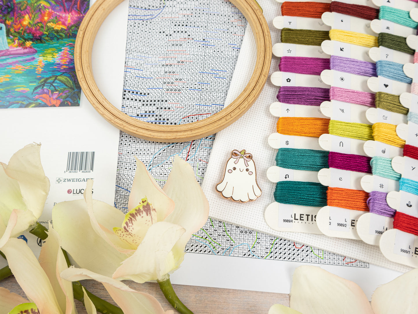 Embroidery hoop, thread spools, and floral elements on a table
