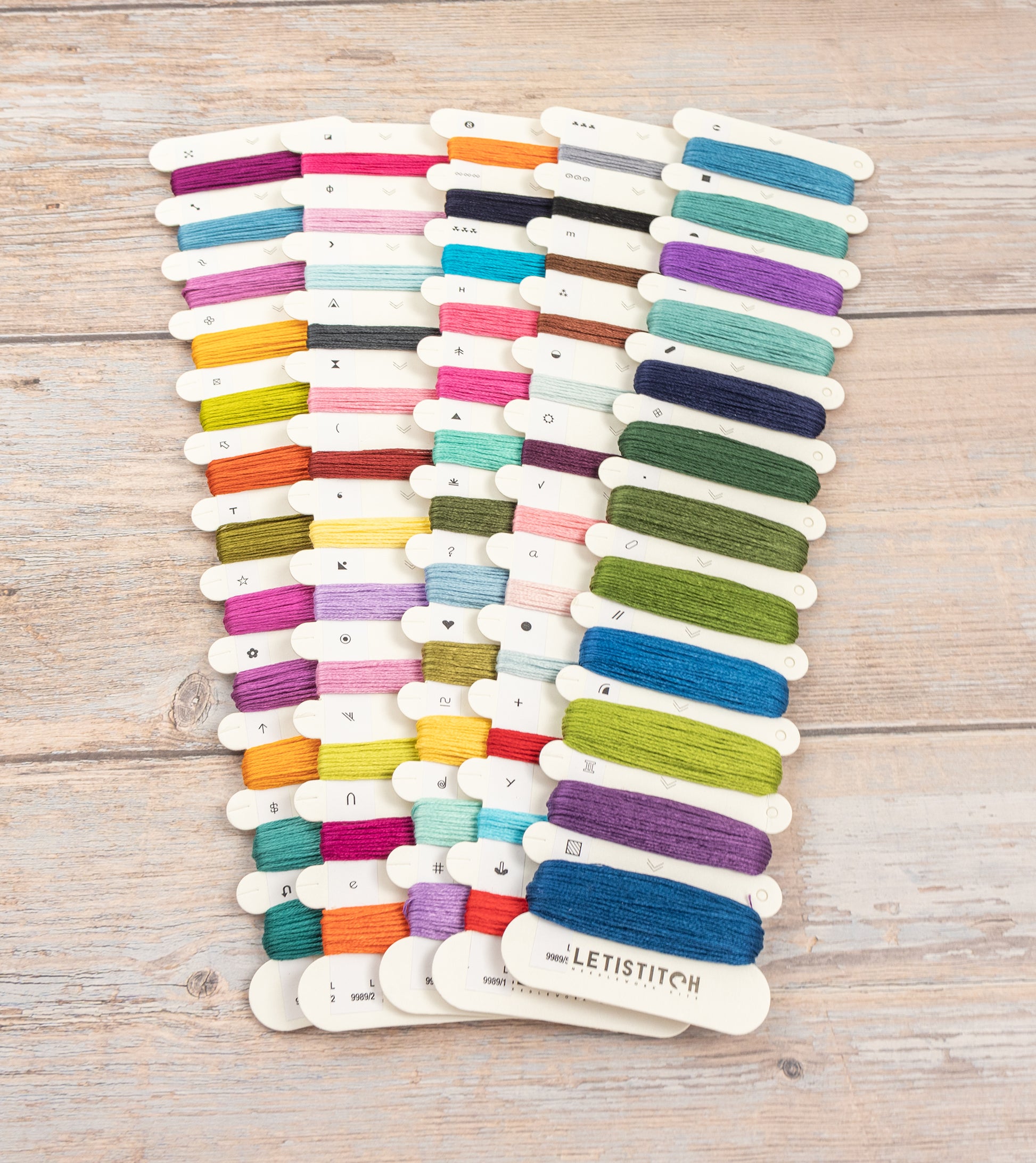Set of colorful embroidery threads on a wooden surface with 'LetiStitch' branding.