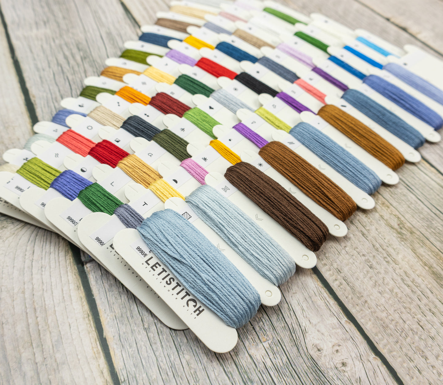 Assorted embroidery thread colors on a wooden surface with LETISTITCH branding.