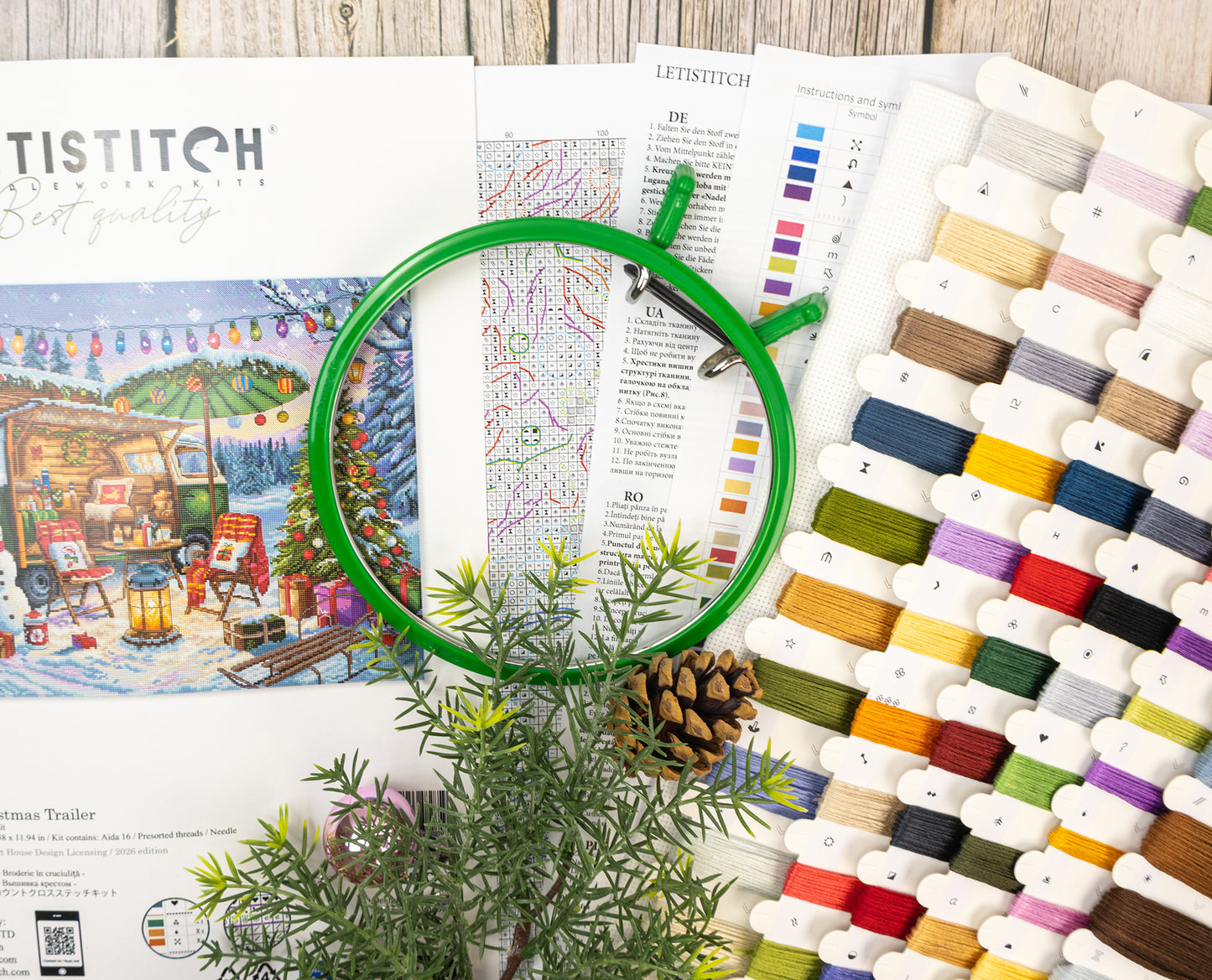 Embroidery hoop with thread spools and pattern book on a wooden surface