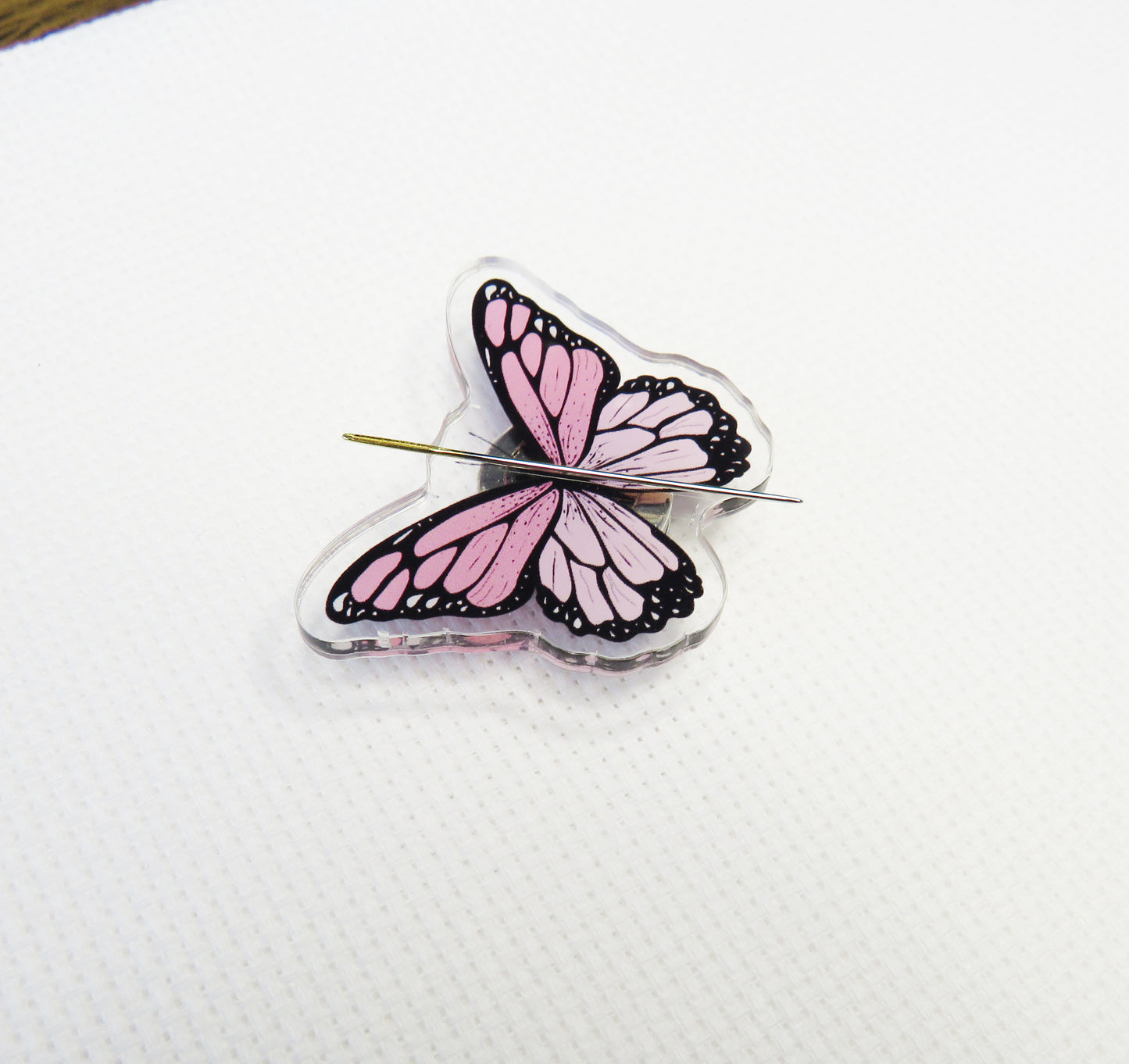 Pink butterfly-shaped needleminder on a white background