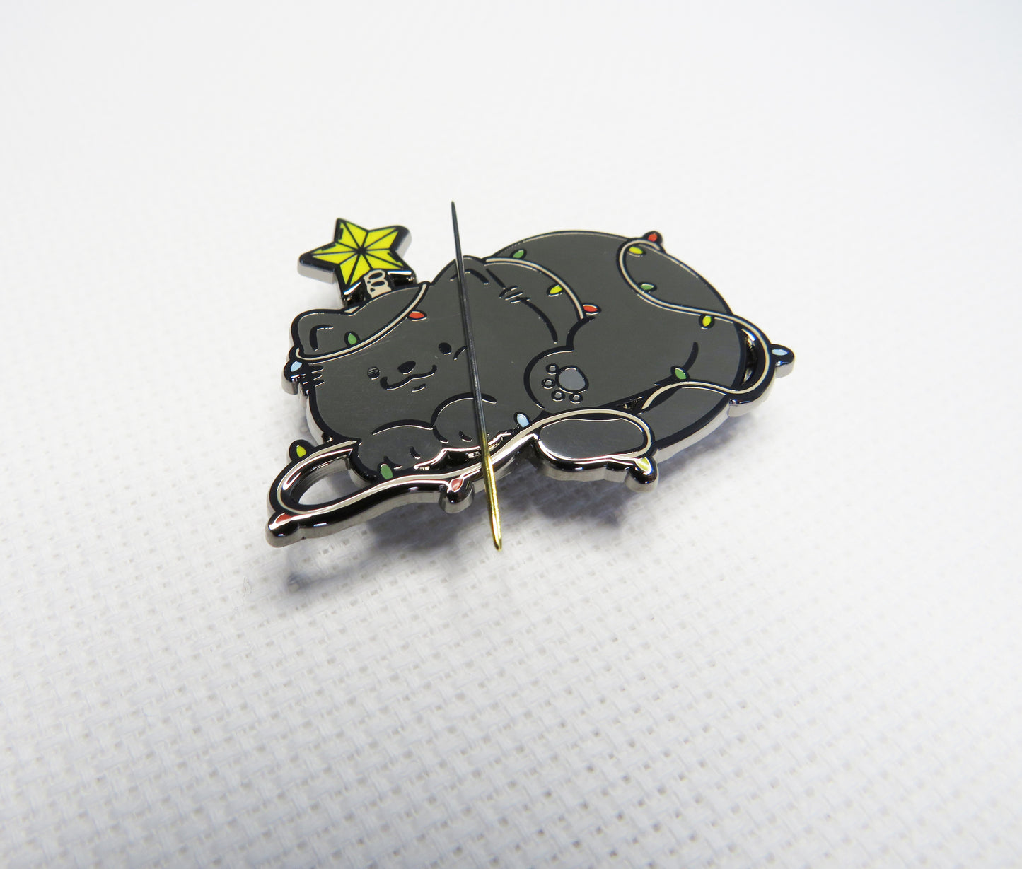 Metallic cat-shaped  needleminder with a star on a white background