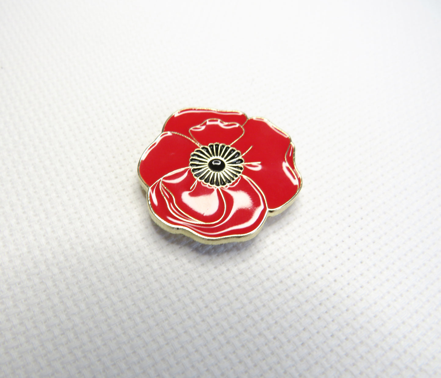 Red poppy flower needleminder on a textured white background