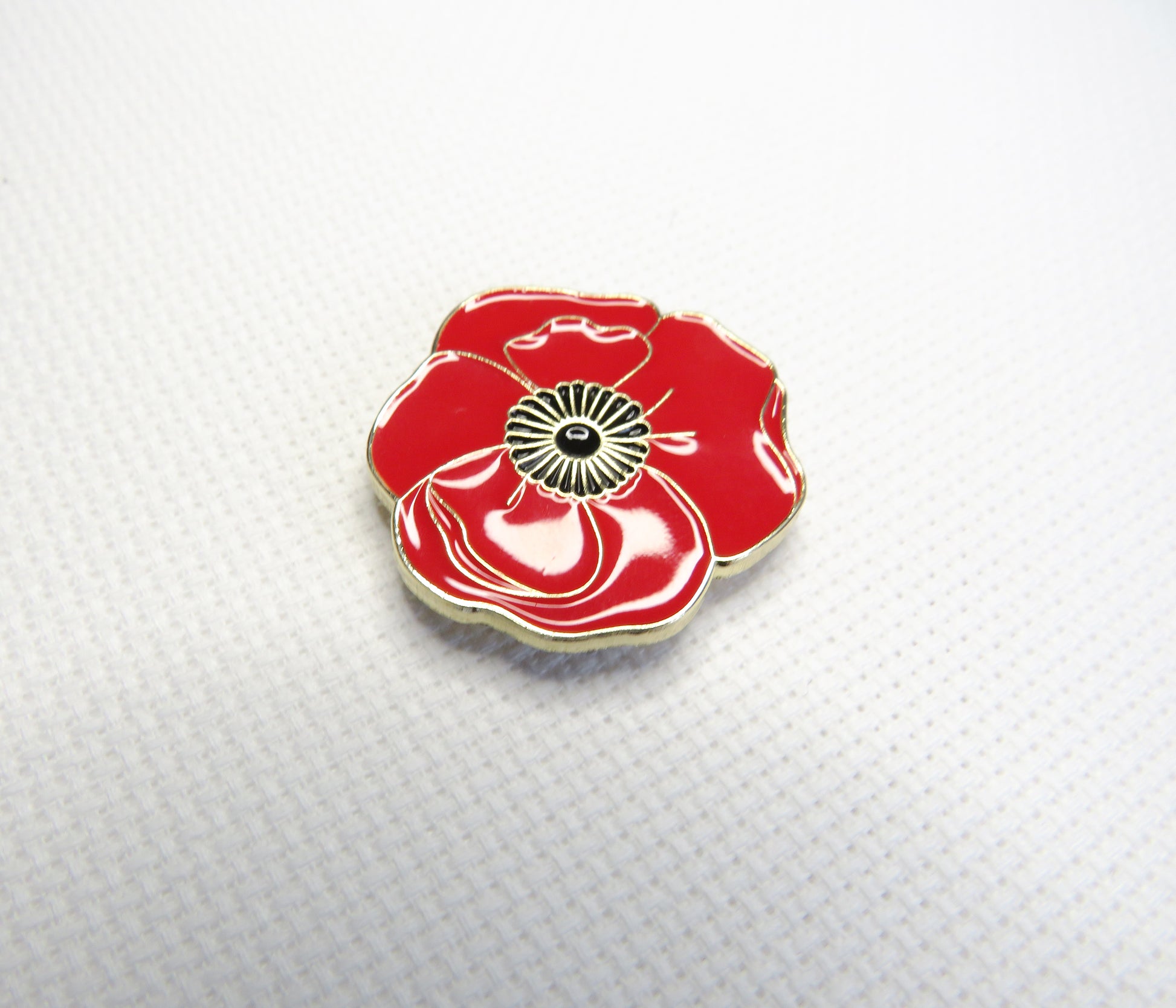 Red poppy flower needleminder on a textured white background