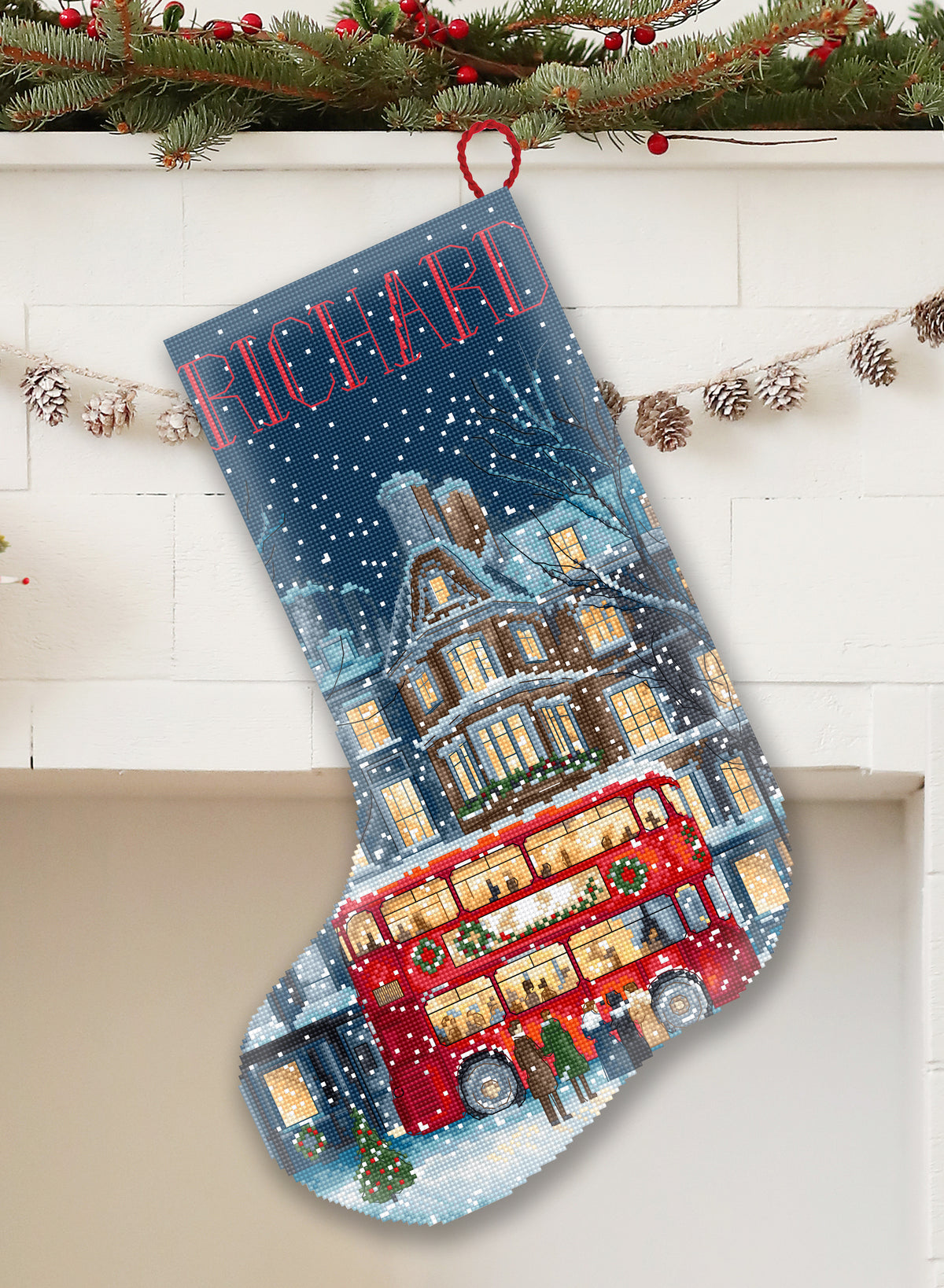 Christmas stocking with a red double-decker bus design and snowflakes, hanging on a fireplace.