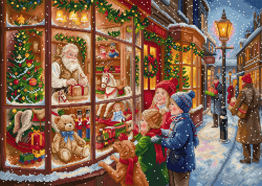 A festive needlepoint or cross-stitch style illustration of a snowy Christmas street scene, showing a toy store window with Santa Claus, teddy bears, gifts, and children looking out at the snowfall.