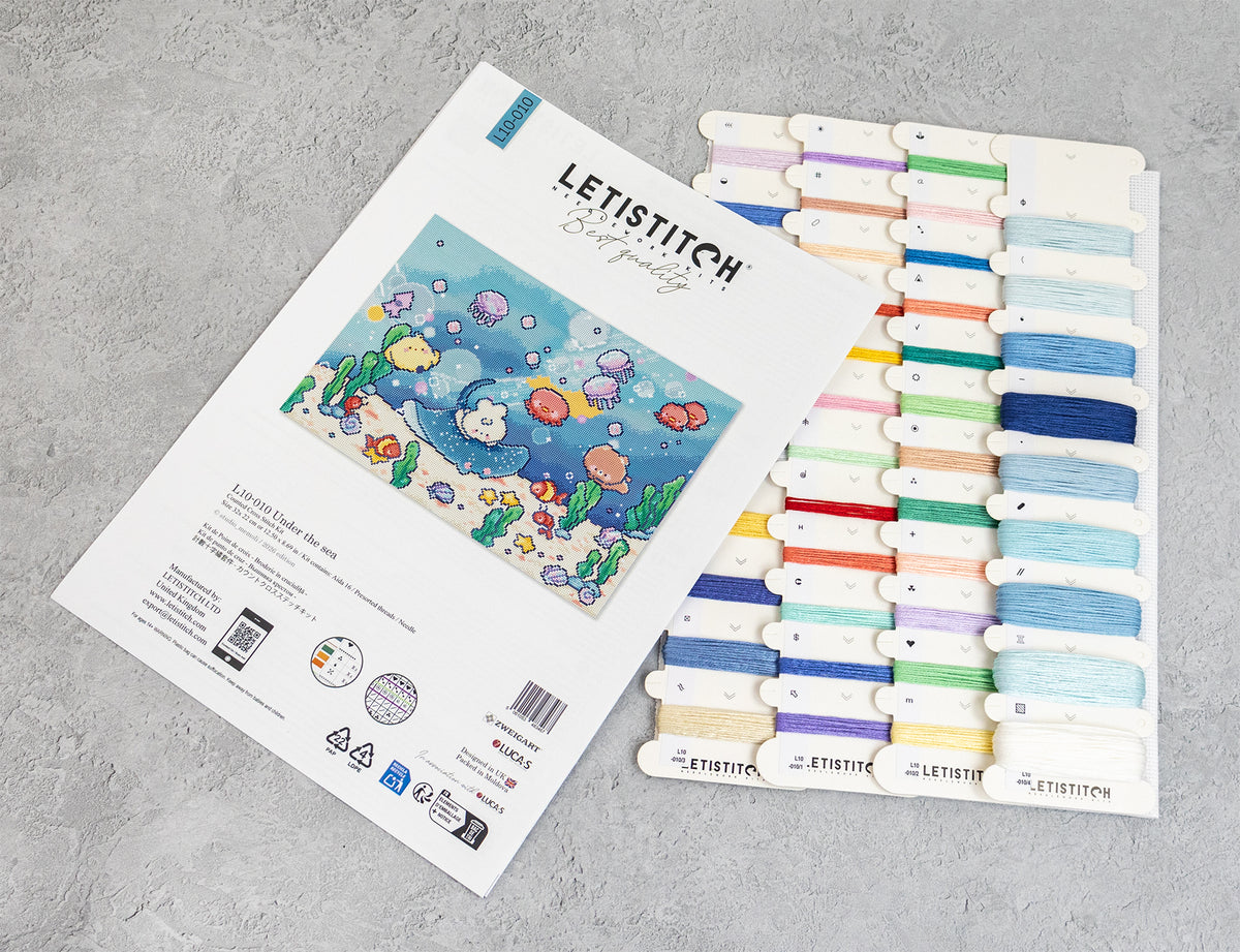 A Letistitch embroidery kit set displayed on a gray textured surface, showing the white instruction booklet with an underwater sea-creature design and a matching card holding multiple colorful thread spools.