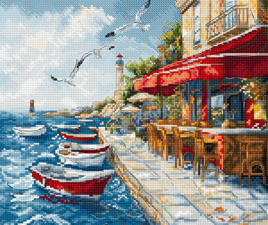 Seaside scene with boats, a lighthouse, and a restaurant with red awnings.