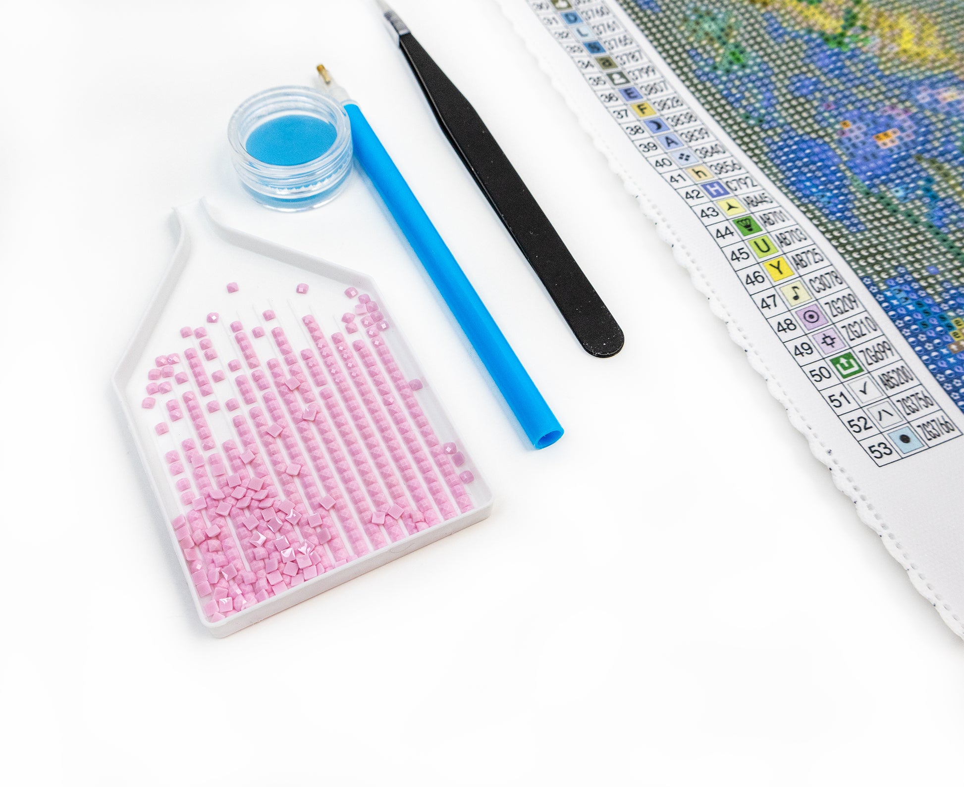 Diamond painting kit with crystals, tools, and a color chart on a white background