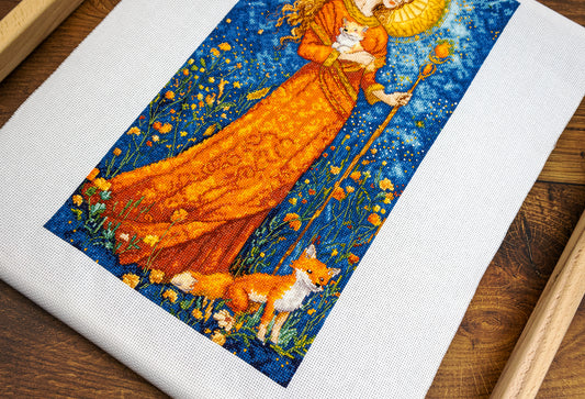 Embroidery of a woman in an orange dress with a fox on a wooden surface