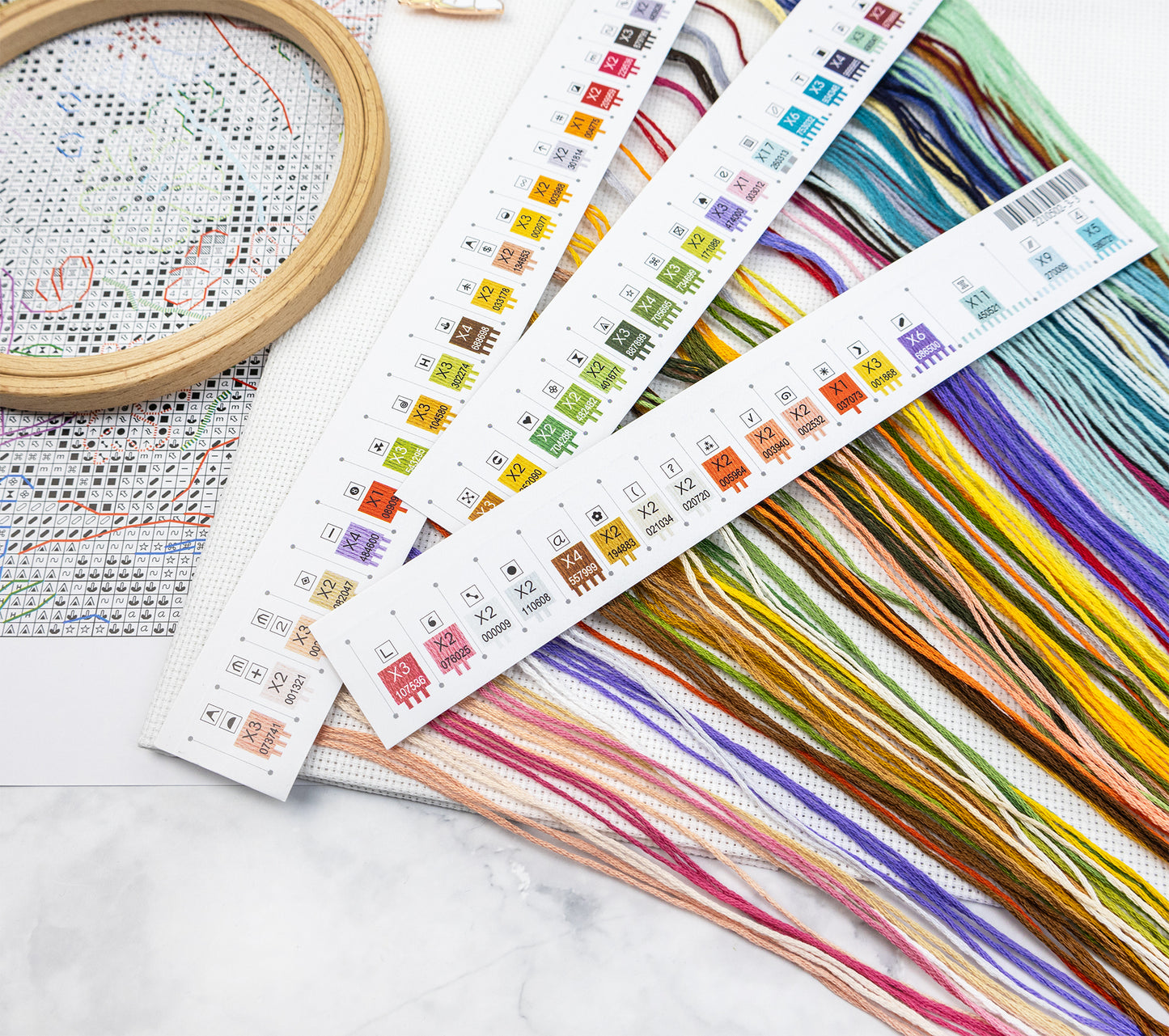 Colorful embroidery floss with patterned cards on a marble surface