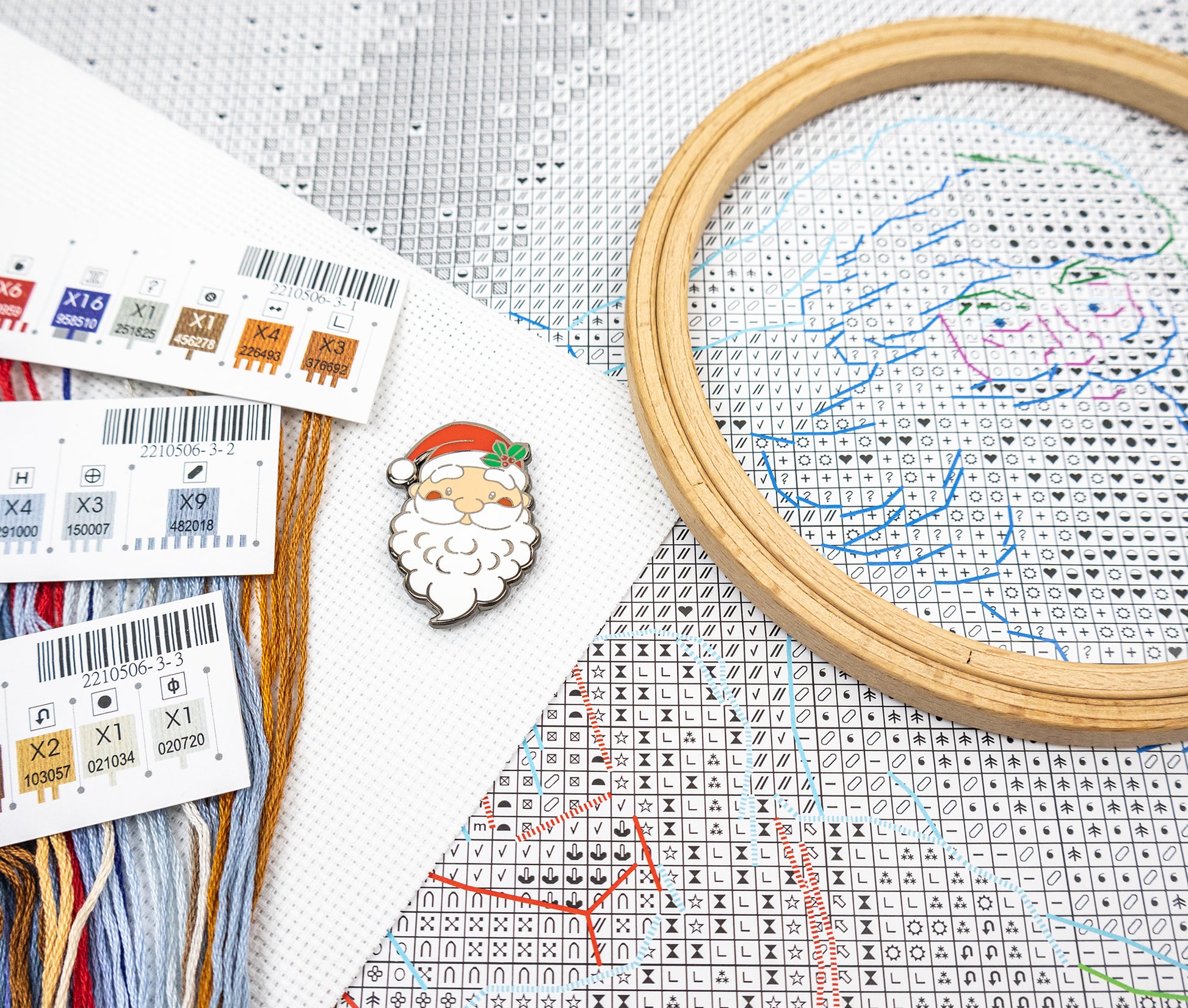 Cross-stitching materials including an embroidery, thread, and a pattern with a Santa Claus design.