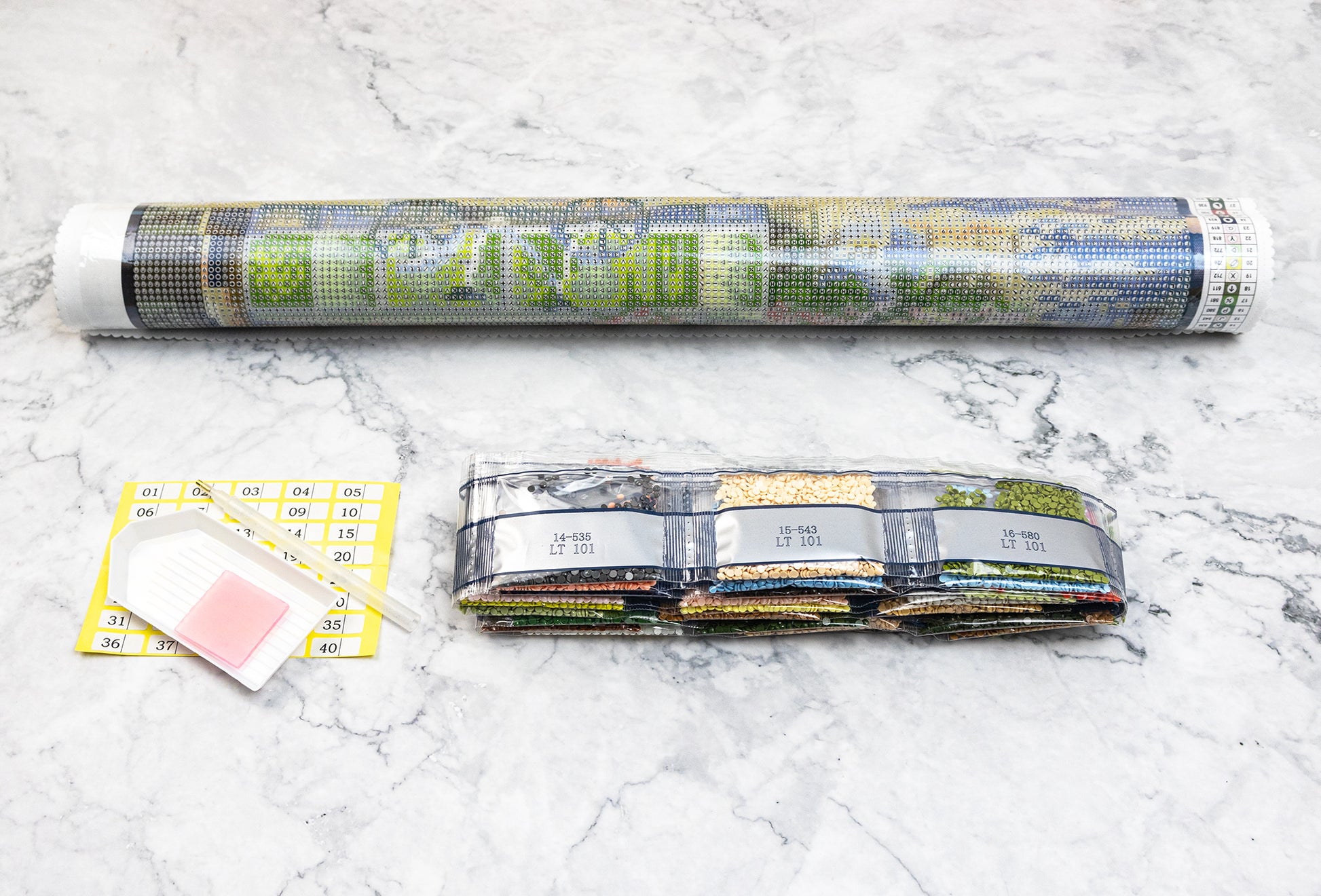 Diamond painting kit Dazzle Dots components on a marble surface