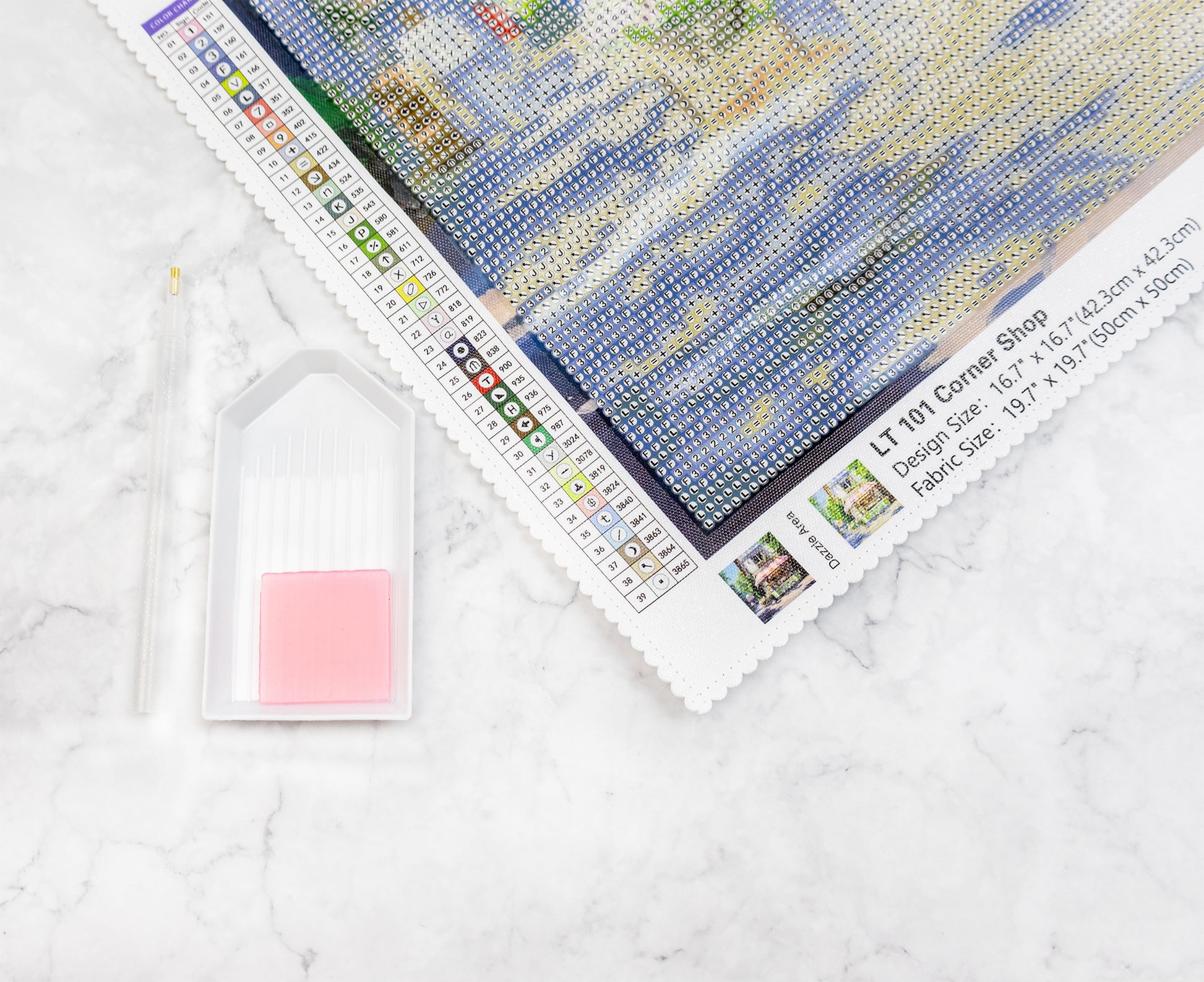 Crystal art pattern with a pink square jelly wax and stylus on a light gray surface