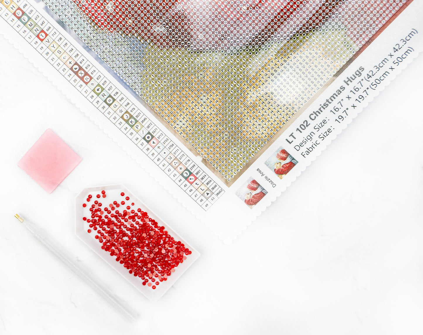 Diamond painting materials including fabric, red crystals, and a stylus on a white background