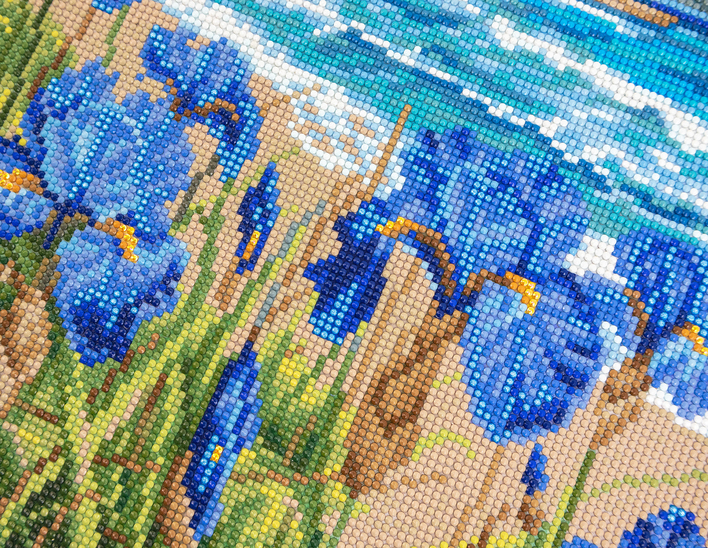 Close-up of a diamond painting with blue flowers and green grass