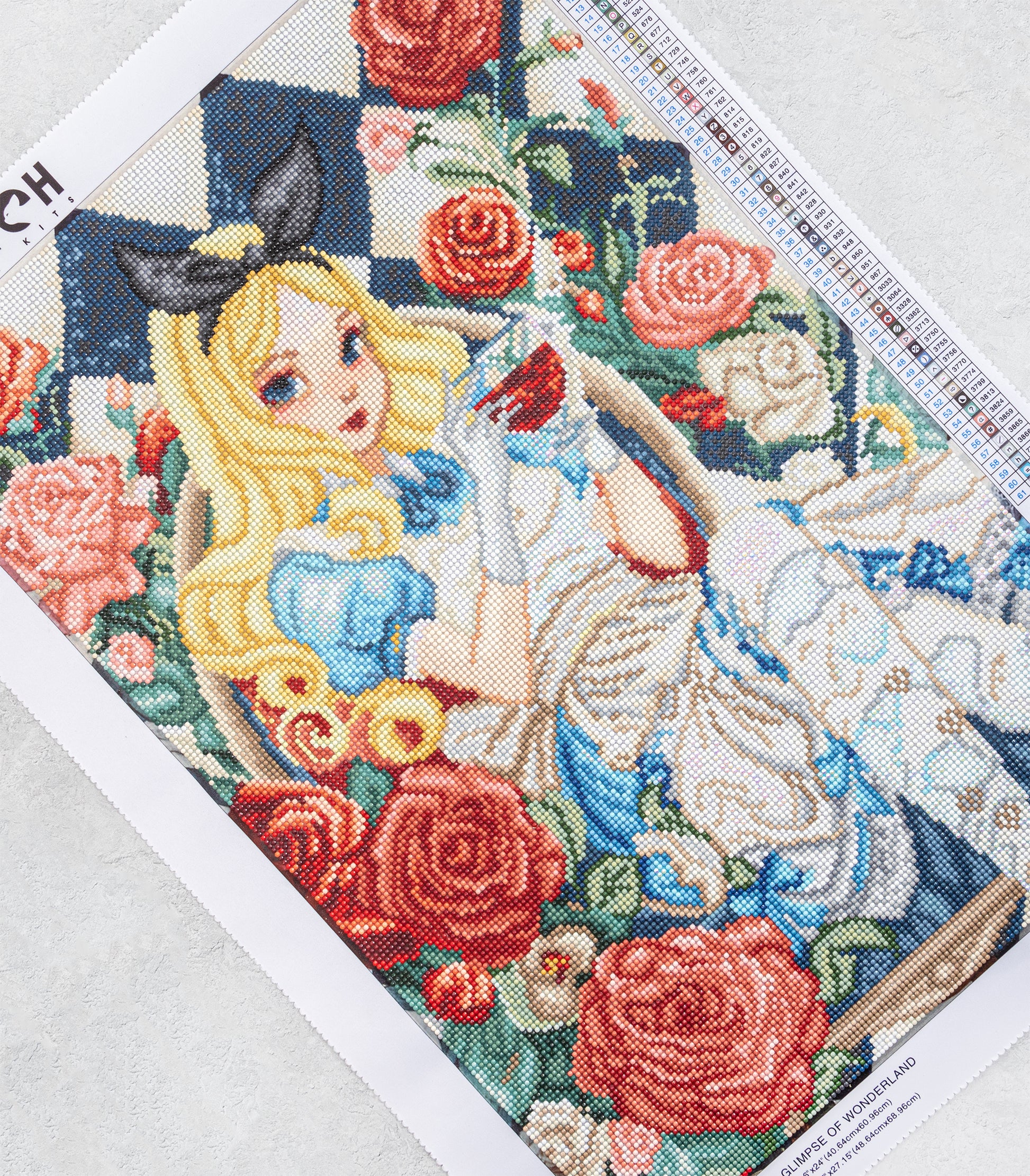 Diamond Art piece of art featuring a character with long blonde hair and blue dress, surrounded by flowers on a white background.