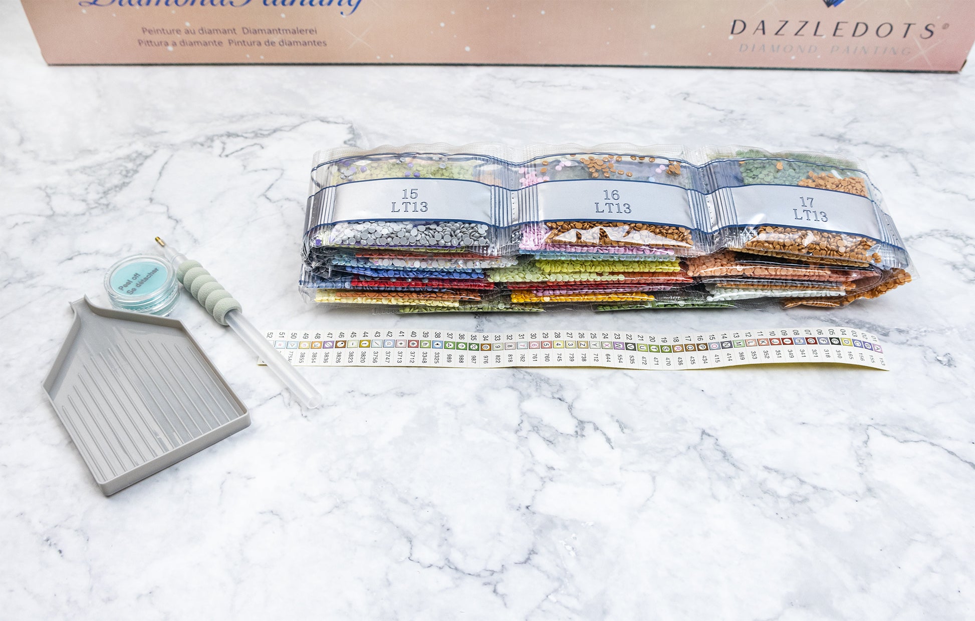 Diamond Painting kit tools and components on a marble surface