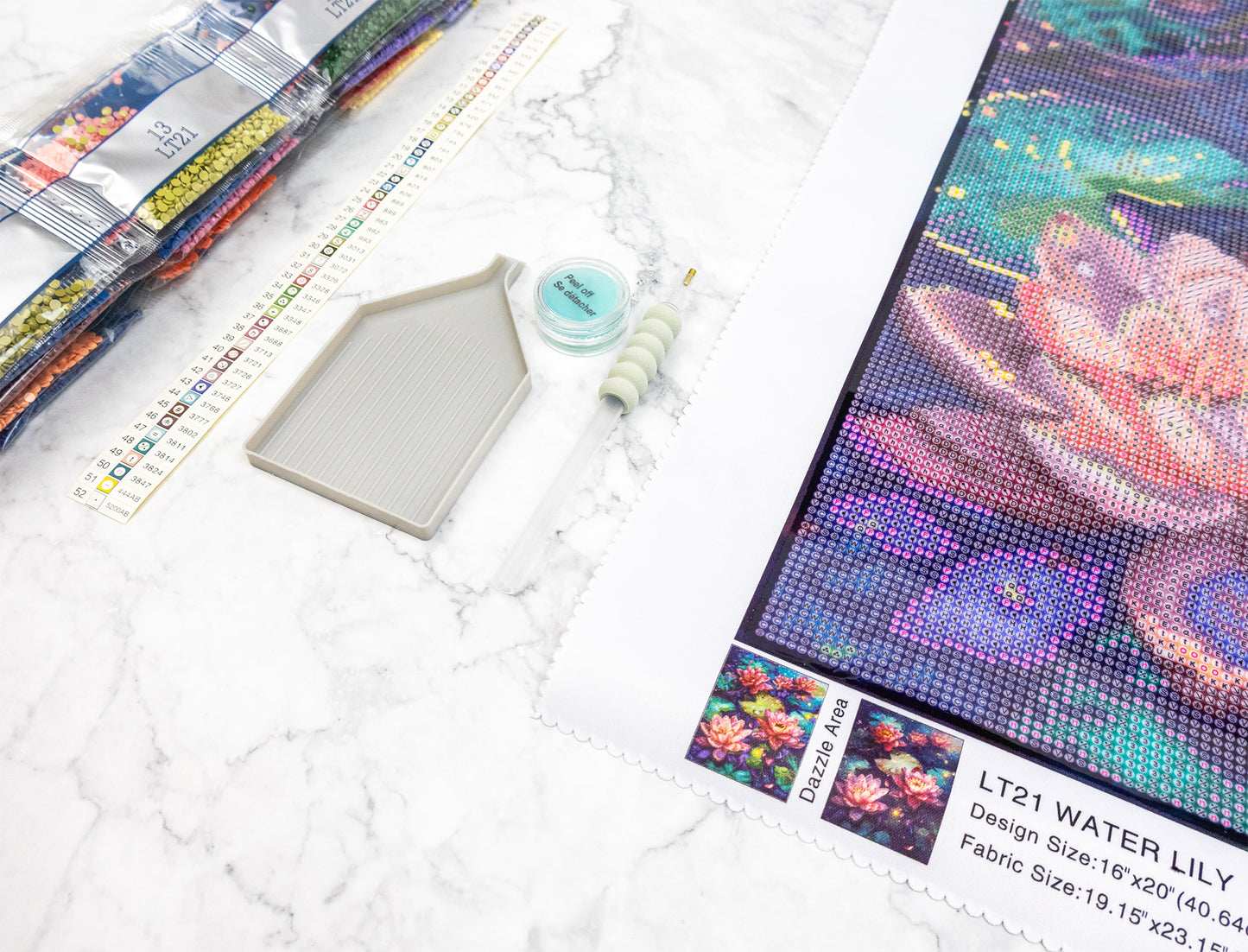 Diamond painting kit with tools and materials on a marble surface